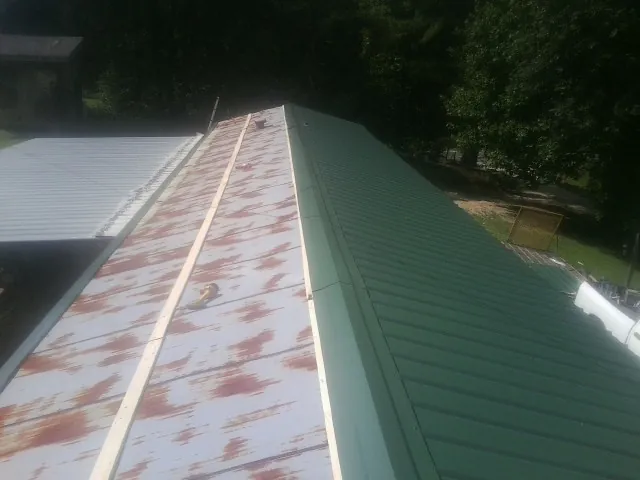 Old rusted panels beside newly installed green metal roofing — Wind Damage Roof Repair by Roofing Brothers in Havana