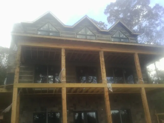 Dormers and porch framing on a large log home under construction — Roof Coating work by our crew in Havana