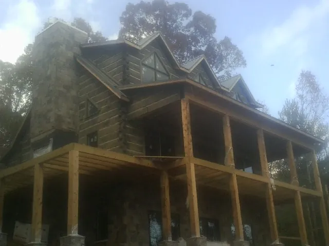 Stone chimney and dormers on a large log home with a timber porch in Havana