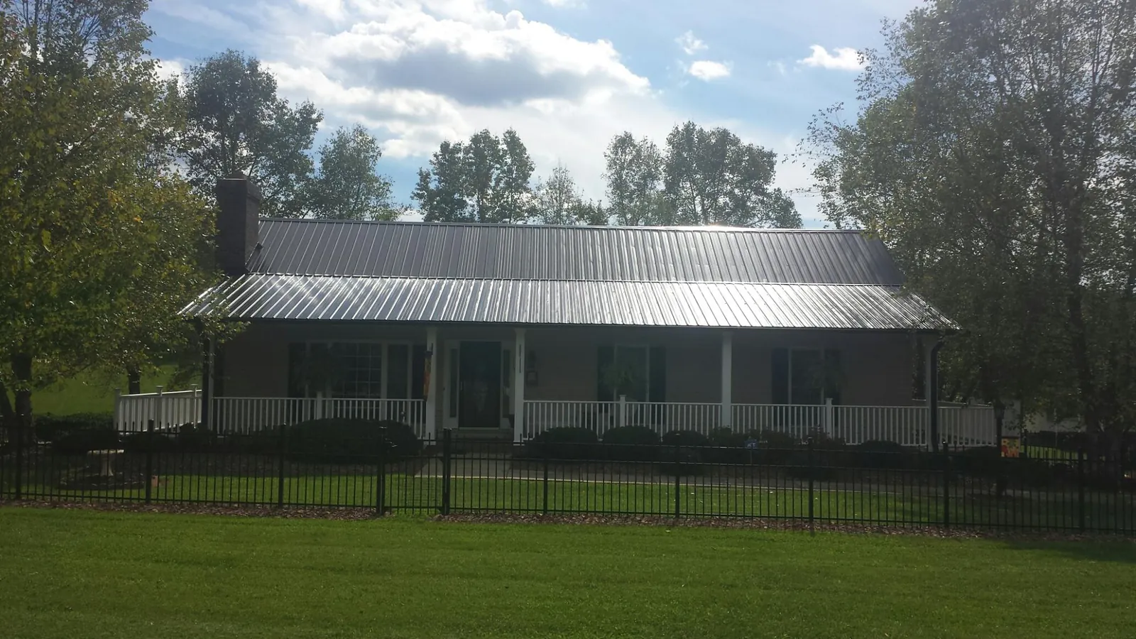 Gray metal roof on a brick ranch with a full width front porch — Gutter Guard Installation work by our crew in Havana