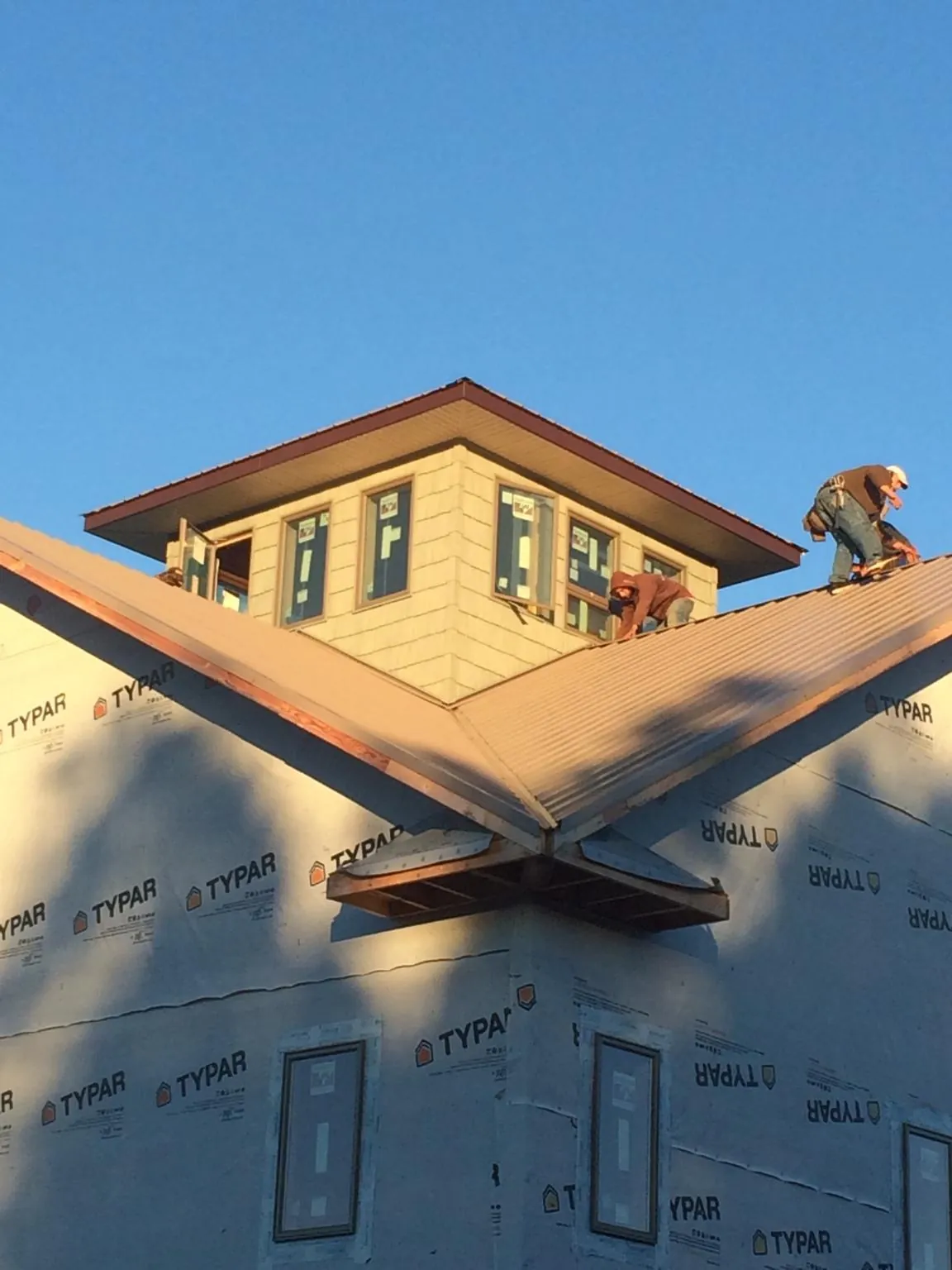 Roofers working around a rooftop cupola on a new metal roof at sunset — Roof Waterproofing in Havana by Roofing Brothers